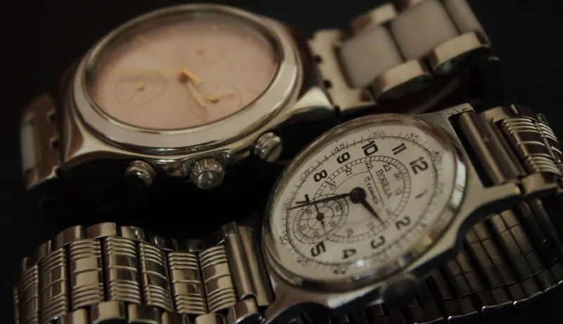 Two vintage steel watches lying together, one a chronograph