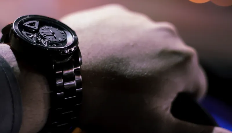 A black watch on a wrist, shot in low light with city bokeh behind